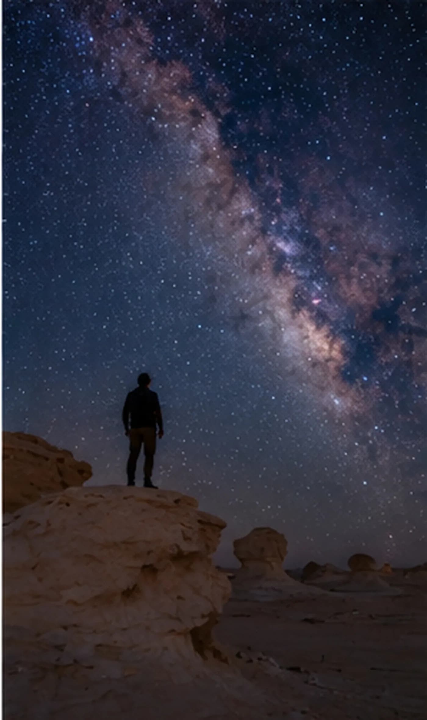 A stargazer on a chalk rock under the Milky Way