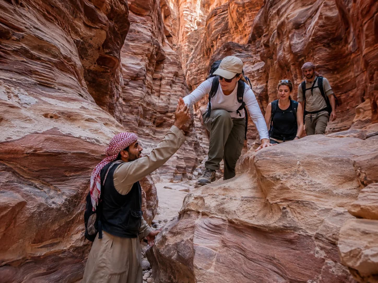 The guide helping a hiker over a rock step in the canyon